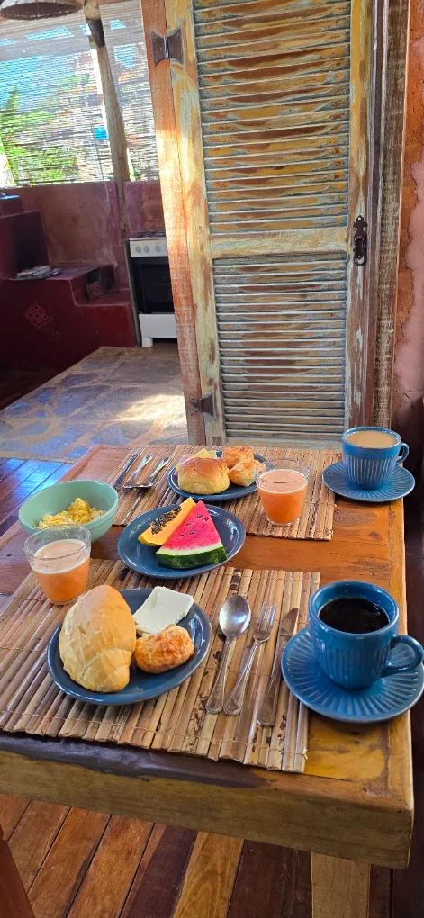 Mesa de madeira com café, sucos, frutas e pães para dois